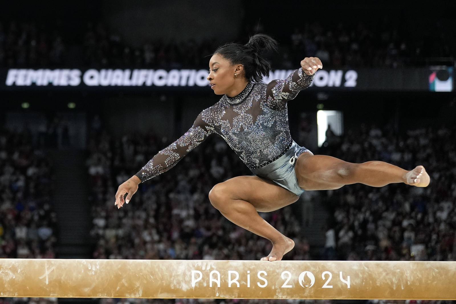 Simone Biles is on the Olympic gymnastics competition floor in front of